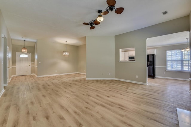 unfurnished living room featuring baseboards, ceiling fan with notable chandelier, visible vents, and light wood-type flooring