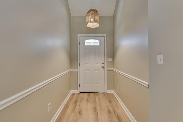 doorway to outside featuring baseboards and light wood finished floors