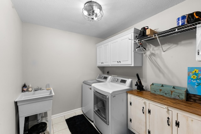 laundry room with washer and dryer, cabinet space, light tile patterned floors, baseboards, and a textured ceiling