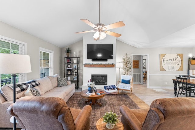living room with lofted ceiling, a fireplace, a ceiling fan, wood finished floors, and baseboards