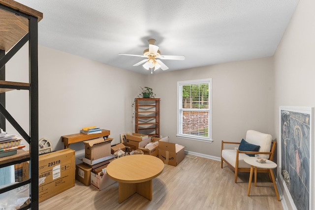 sitting room featuring light wood-type flooring, a ceiling fan, and baseboards