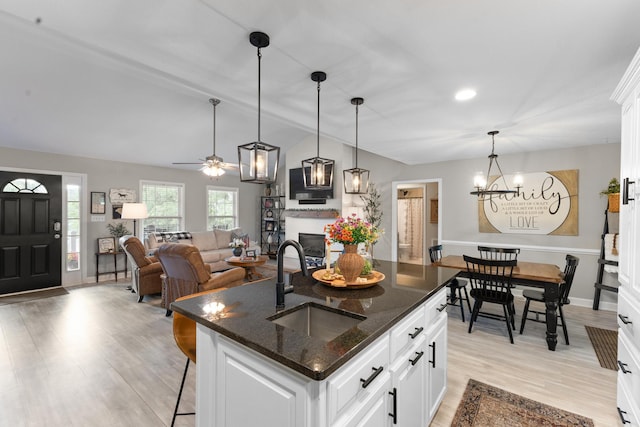 kitchen featuring a sink, vaulted ceiling, a breakfast bar, light wood-type flooring, and a chandelier