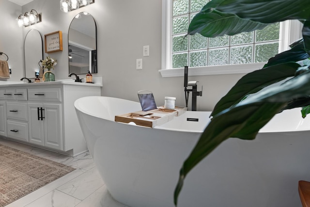 bathroom featuring marble finish floors, a freestanding bath, and double vanity