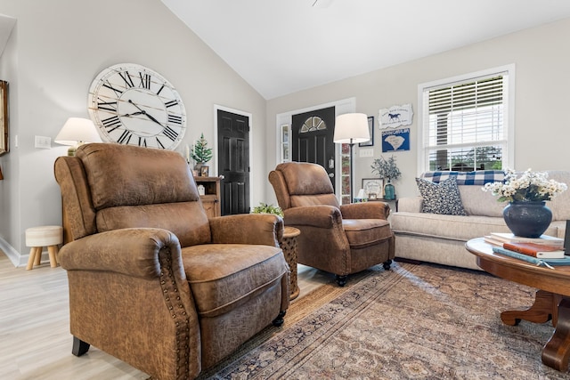 living area with light wood-style floors, vaulted ceiling, and baseboards