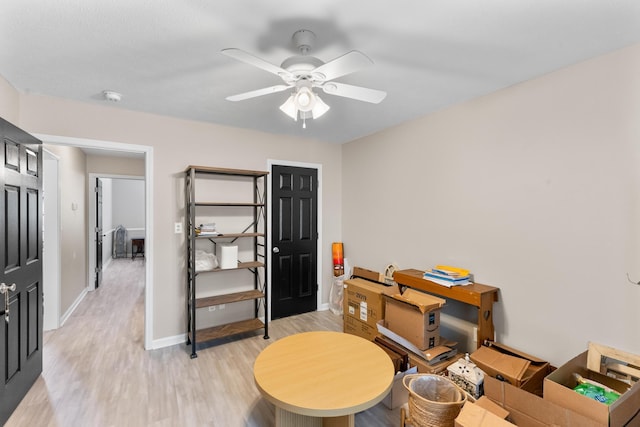 interior space with light wood finished floors, a ceiling fan, and baseboards
