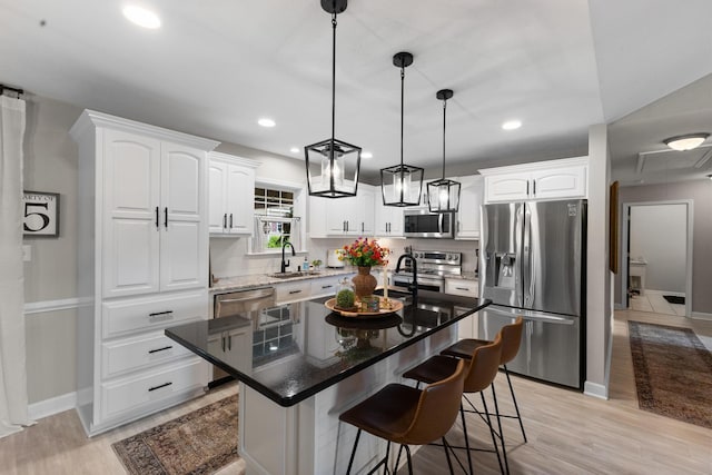 kitchen featuring stainless steel appliances, a sink, baseboards, white cabinetry, and a breakfast bar area