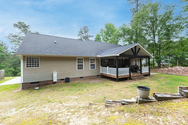 back of house with crawl space, a lawn, roof with shingles, and a deck