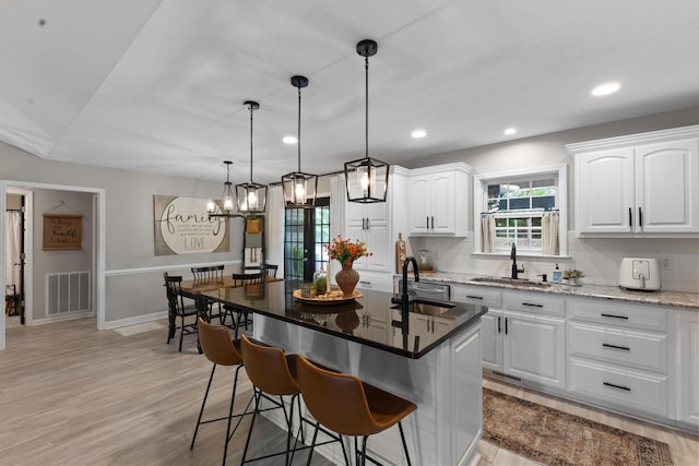 kitchen with a sink, white cabinetry, a breakfast bar area, backsplash, and recessed lighting