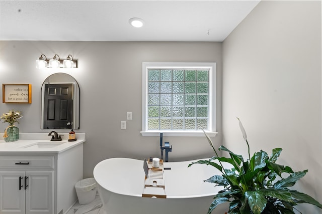 bathroom featuring marble finish floors, a freestanding bath, and vanity