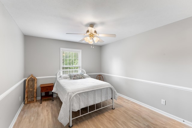 bedroom featuring wood finished floors, baseboards, and a ceiling fan