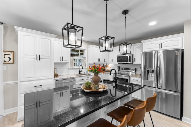 kitchen with stainless steel appliances, a sink, white cabinetry, a breakfast bar, and recessed lighting