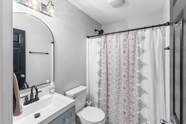 bathroom with toilet, vanity, and curtained shower