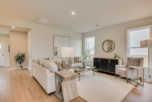 living room featuring light wood finished floors, visible vents, baseboards, and recessed lighting