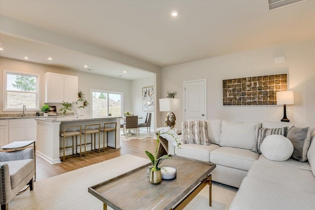 living room with light wood-type flooring, visible vents, and plenty of natural light