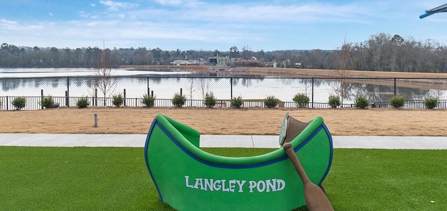 view of community with a lawn, a water view, and fence