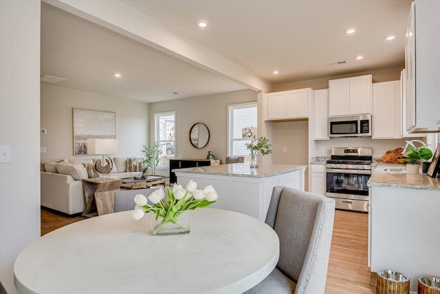 dining area with light wood-style flooring, visible vents, beam ceiling, and recessed lighting