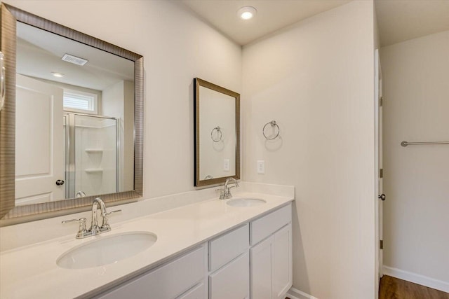 bathroom featuring visible vents, a sink, a shower stall, and double vanity