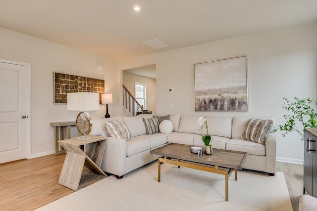 living area with light wood finished floors, baseboards, and stairway