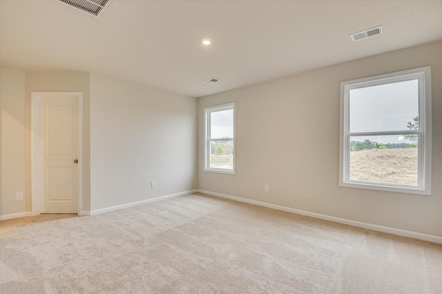 unfurnished room with light carpet, visible vents, and baseboards