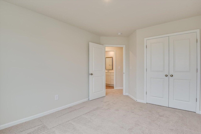 unfurnished bedroom with light carpet, baseboards, and a closet