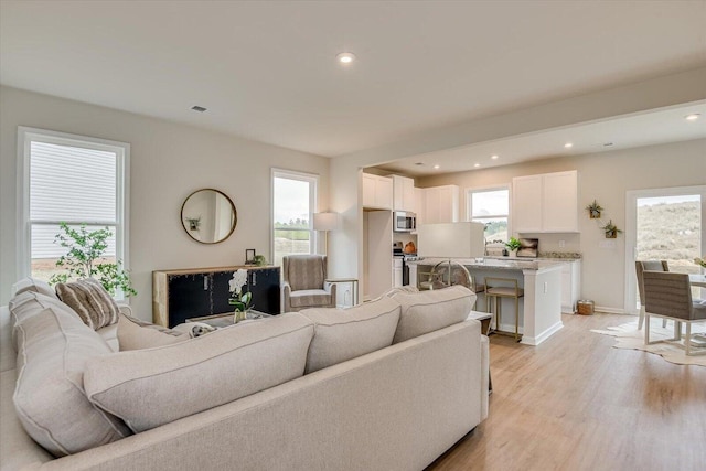 living room featuring light wood-type flooring, visible vents, baseboards, and recessed lighting