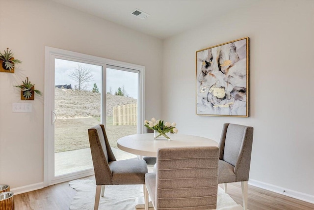 dining room featuring wood finished floors, visible vents, and baseboards