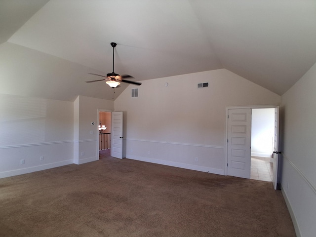 empty room with visible vents, vaulted ceiling, and carpet flooring