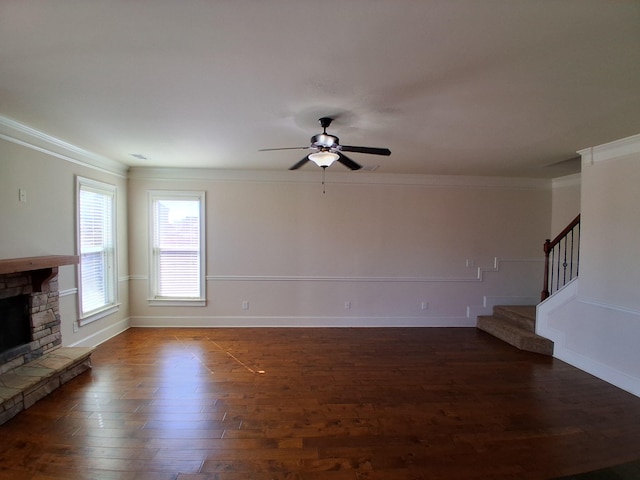 unfurnished living room featuring stairs, a stone fireplace, dark wood finished floors, and crown molding