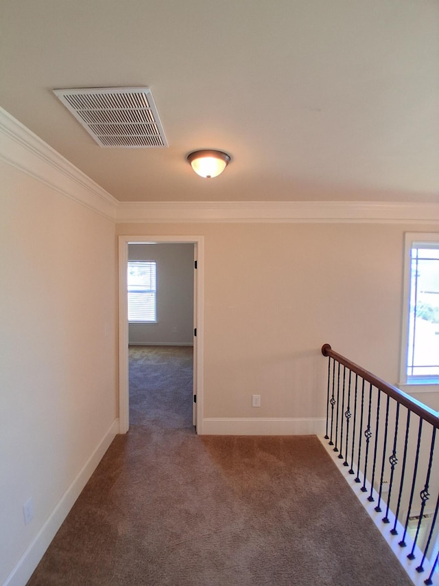 hallway featuring carpet floors, visible vents, crown molding, and baseboards