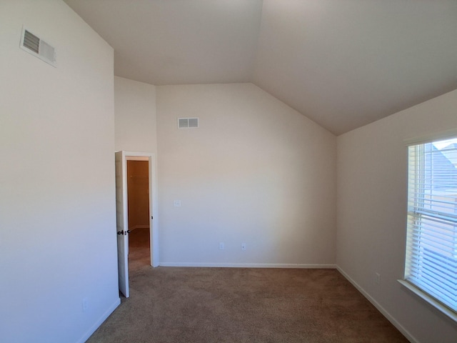 empty room with baseboards, visible vents, vaulted ceiling, and carpet flooring