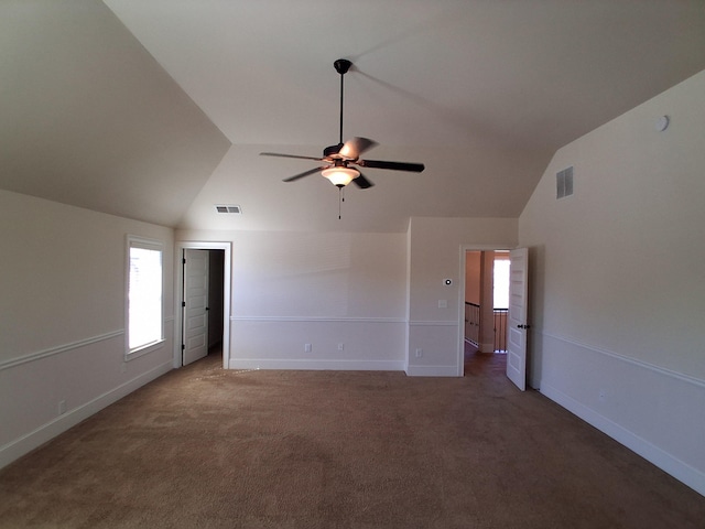 carpeted spare room featuring vaulted ceiling, a ceiling fan, visible vents, and baseboards