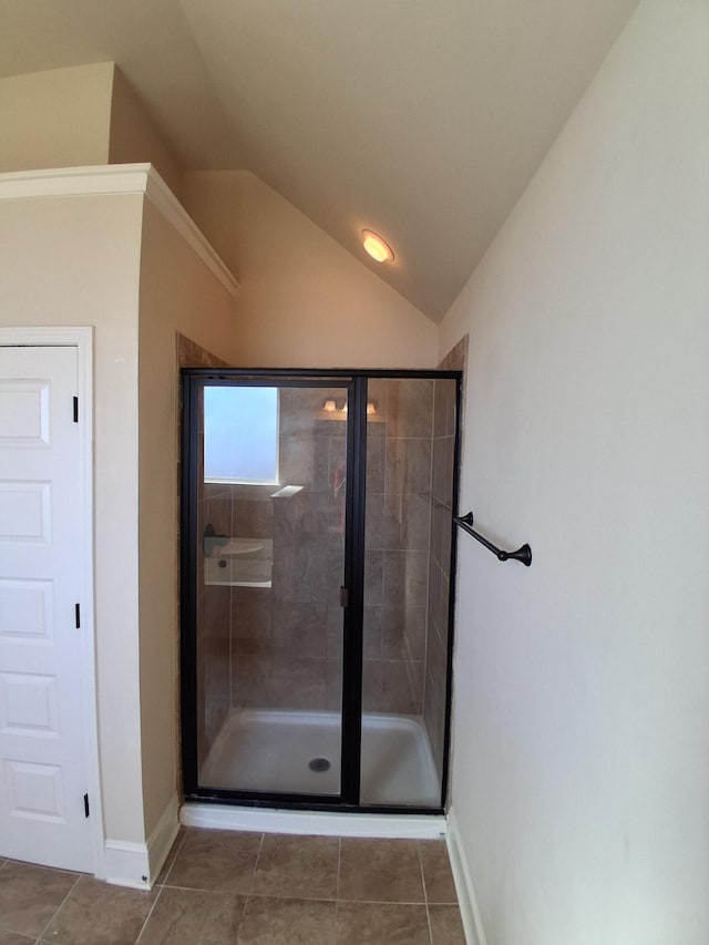 bathroom featuring lofted ceiling, a stall shower, tile patterned flooring, and baseboards