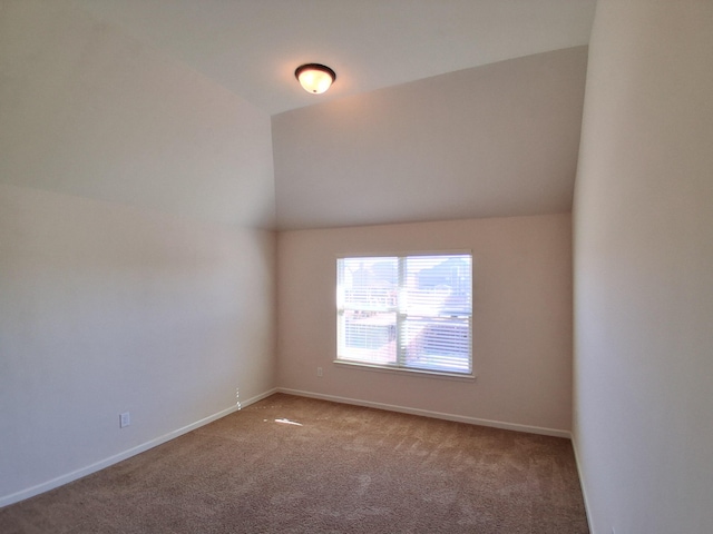 empty room featuring lofted ceiling, carpet, and baseboards