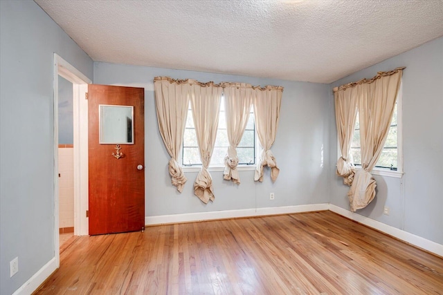 unfurnished room with plenty of natural light, a textured ceiling, and hardwood / wood-style flooring