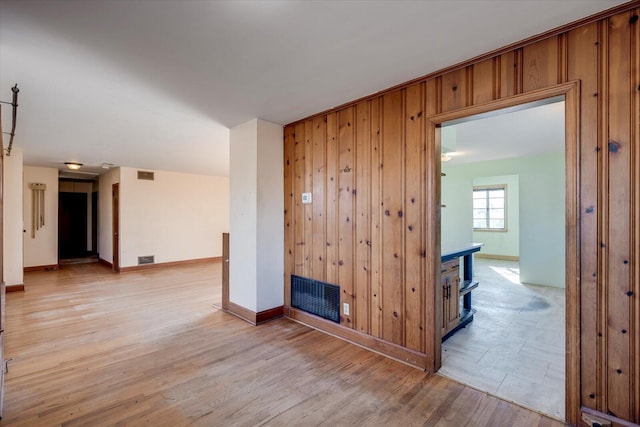 spare room with wooden walls, visible vents, and light wood finished floors