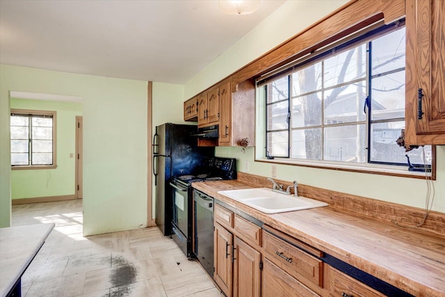 kitchen featuring baseboards, wooden counters, a sink, black appliances, and under cabinet range hood