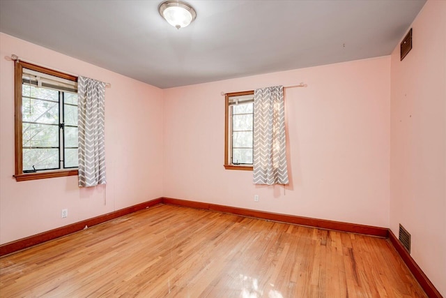 unfurnished room with visible vents, light wood-style flooring, and baseboards