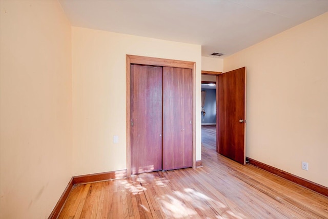 unfurnished bedroom with visible vents, baseboards, a closet, and wood finished floors