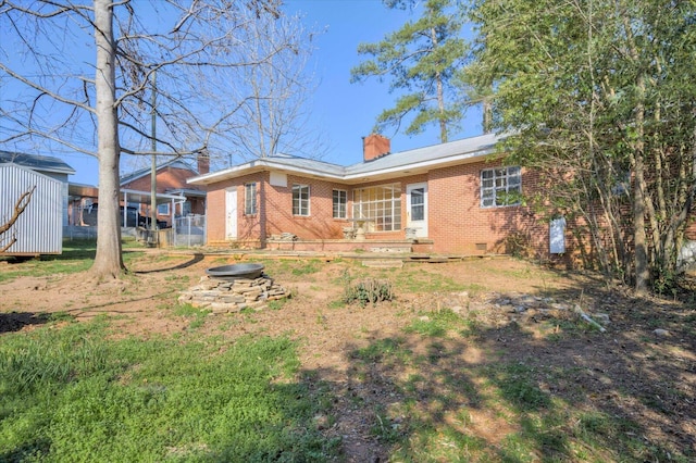 back of property featuring an outdoor fire pit, crawl space, brick siding, and a chimney