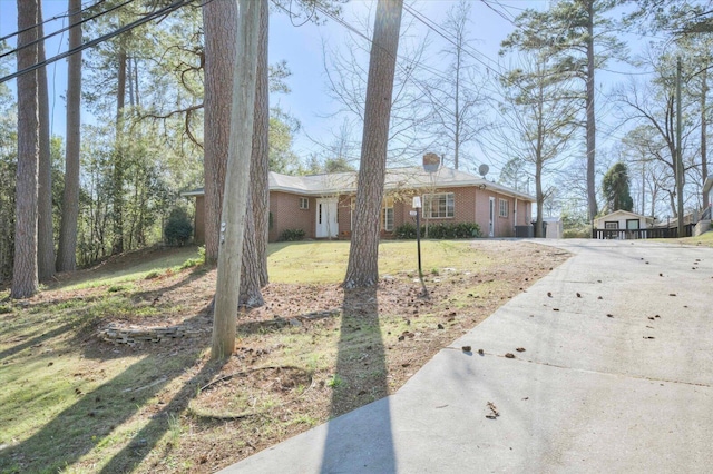 view of front facade with a front lawn, brick siding, and driveway