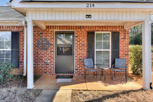 property entrance with brick siding, board and batten siding, and a shingled roof