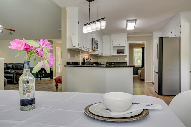 dining space with light wood-type flooring, a ceiling fan, baseboards, and crown molding