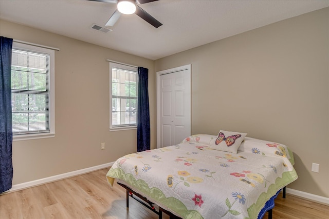 bedroom with light wood-type flooring, visible vents, baseboards, and multiple windows