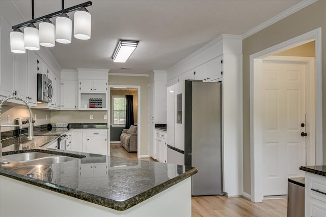 kitchen featuring stainless steel appliances, ornamental molding, a sink, light wood-type flooring, and white cabinetry