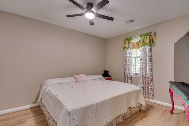 bedroom with wood finished floors, visible vents, a ceiling fan, and baseboards