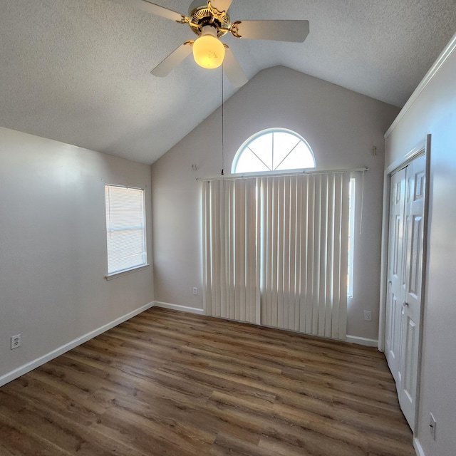 empty room with a textured ceiling, dark hardwood / wood-style floors, ceiling fan, and lofted ceiling