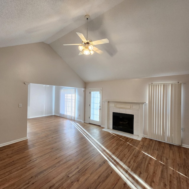 unfurnished living room with ceiling fan, a fireplace, vaulted ceiling, and hardwood / wood-style flooring