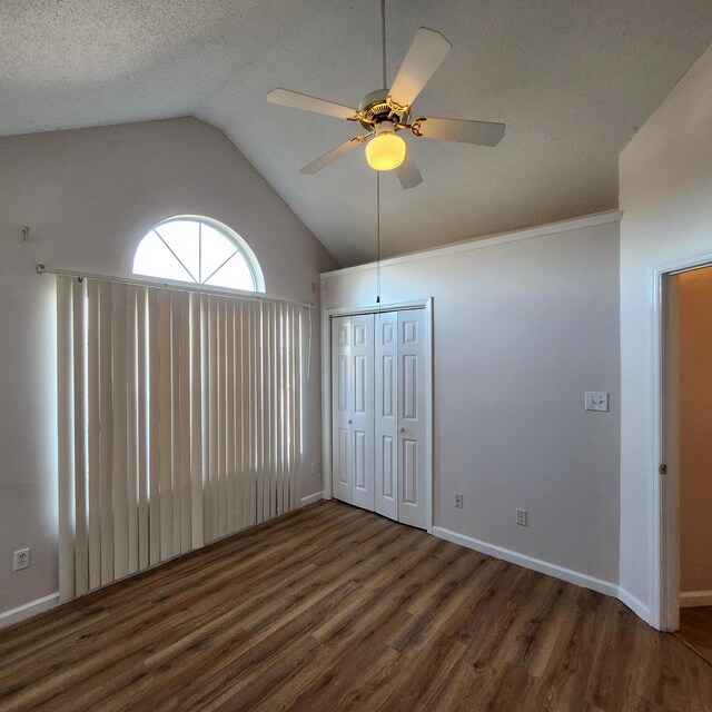 unfurnished bedroom with ceiling fan, dark hardwood / wood-style flooring, a textured ceiling, vaulted ceiling, and a closet