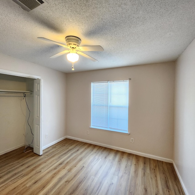 unfurnished bedroom featuring a textured ceiling, light wood-type flooring, a closet, and ceiling fan