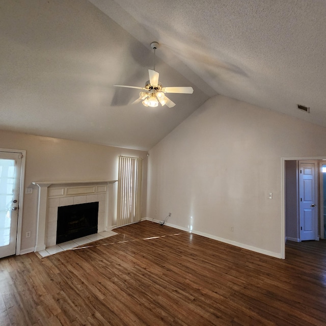 unfurnished living room with ceiling fan, a textured ceiling, lofted ceiling, a tiled fireplace, and hardwood / wood-style flooring